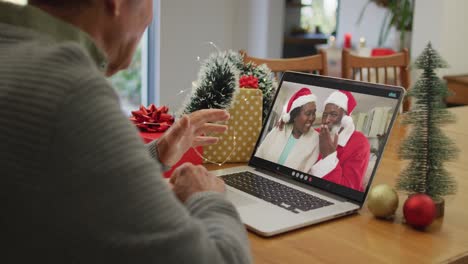 Happy-caucasian-senior-man-on-video-call-with-friends-at-christmas-time