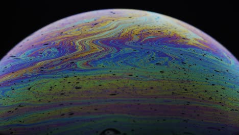 little black bubbles surrounded by colorful hue of rainbow on soap's film