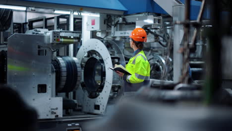 ingeniero enfocado escribiendo un cuaderno en una gran instalación de producción de fabricación.