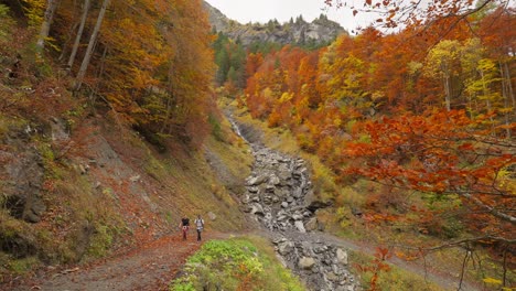 couple hiking up on winding batoni waterfall gravel trail in switzerland