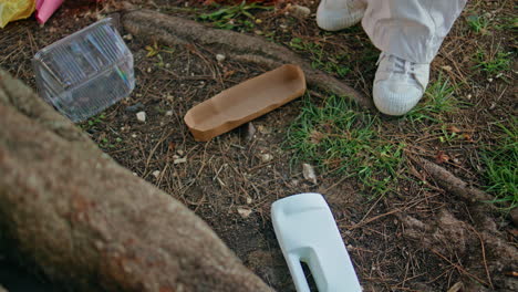 hands taking ground litter in green park closeup. girl activist collecting waste