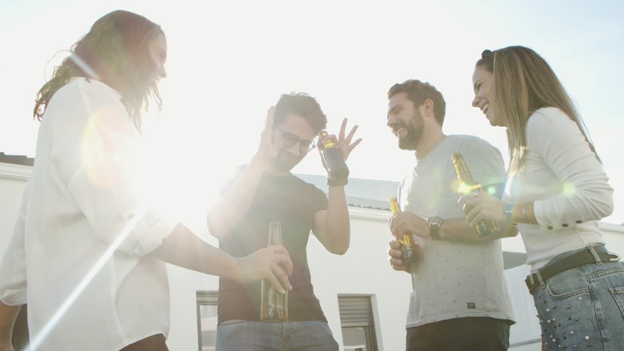 Vista dal basso di amici allegri che ballano con la birra