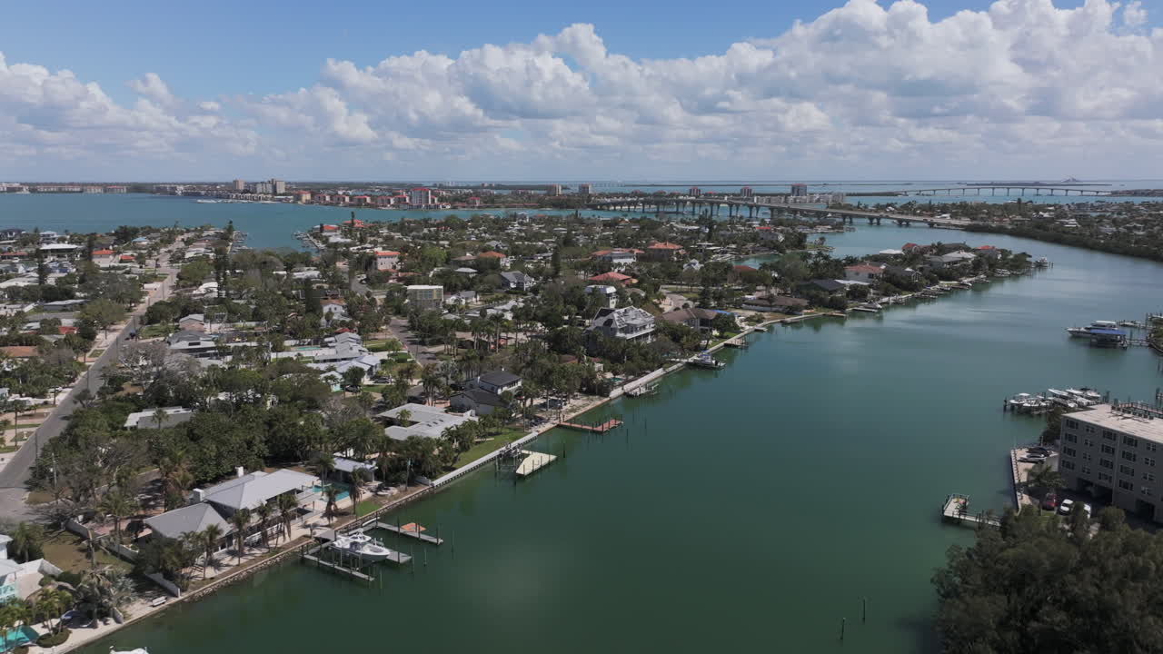 Veduta aerea del quartiere costiero di Belle Vista a Saint Pete Beach che mostra case fronte mare con pontili privati, piscine e il ponte Pinellas Bayway attraverso la baia di Boca Ciega, Florida.