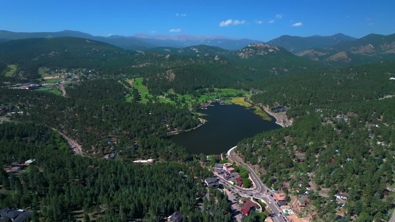 Evergreen Lake House waterfall dam Park and Rec Center Golf Course Keys on the green downtown mountain town summer sunny blue sky flag water dam Colorado aerial drone backwards upwards motion
