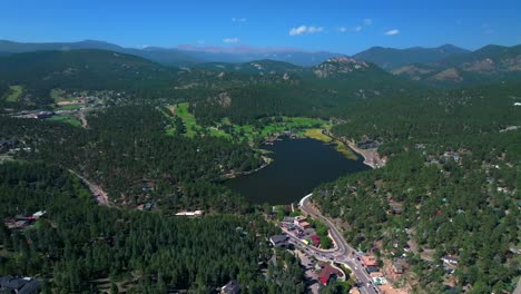 evergreen lake house waterfall dam park and rec center golf course keys on the green downtown mountain town summer sunny blue sky flag water dam colorado aerial drone backwards upwards motion