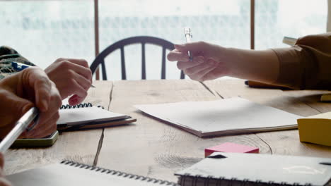 close up view of the hands of students draw on a paper