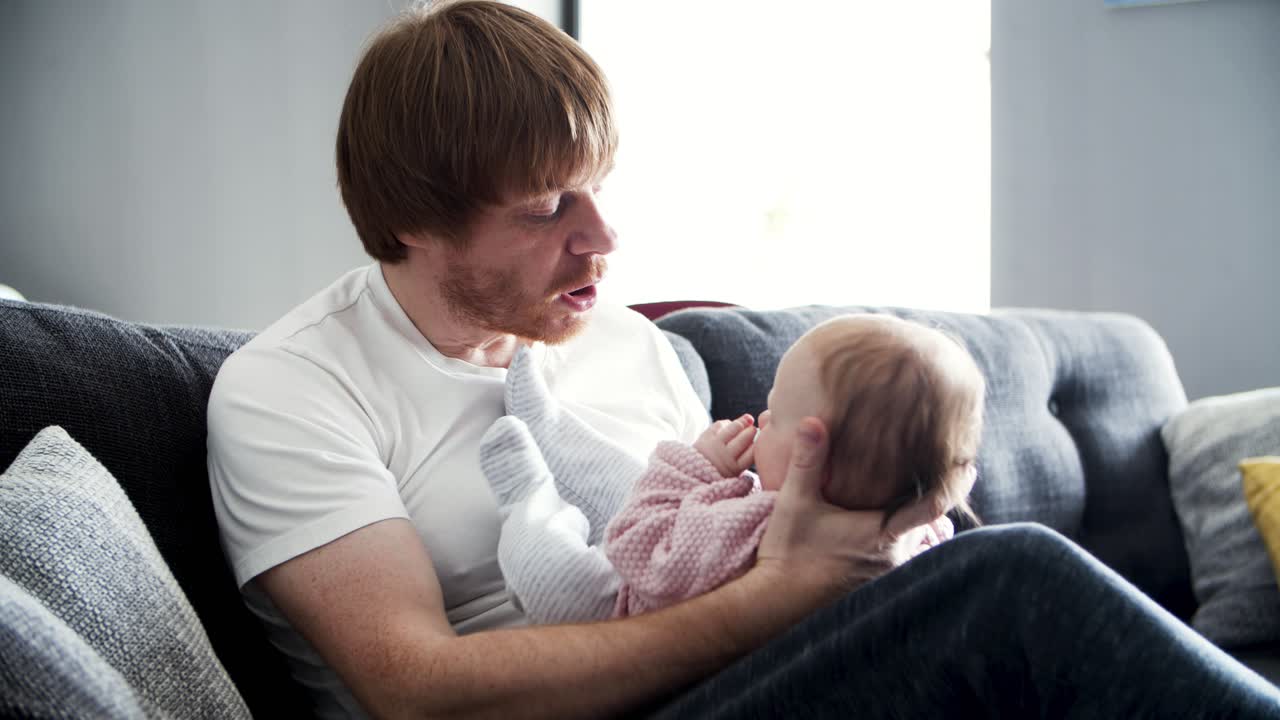 Focused dad holding baby daughter and talking to her