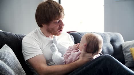 focused dad holding baby daughter and talking to her