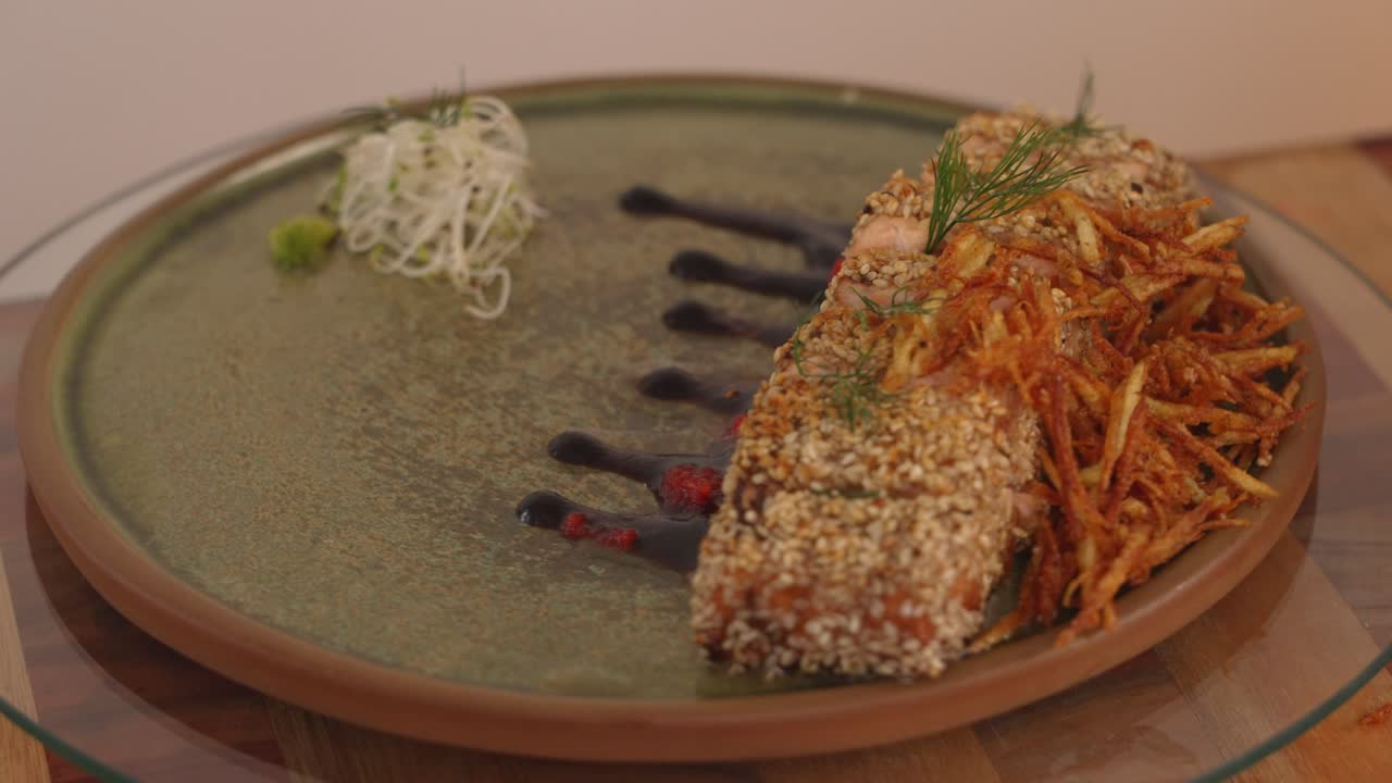 Complete dish of delicious seared crust tataki salmon with citrus ponzu sauce, garnish with sesame seeds and deep fried pai potatoes on the side spinning on a lazy susan turntable