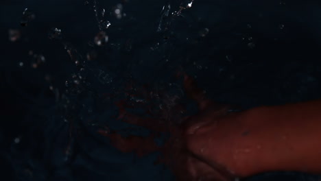 manos sumergiéndose en el agua negra