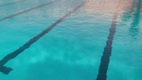 piscine d'eau avec des reflets du coucher de soleil et des voies de natation au fond