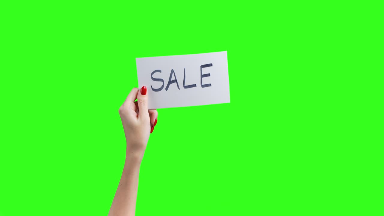 Optagelse af kvindelige hænder der viser et hvidt ark med "udsalg" på grøn baggrund