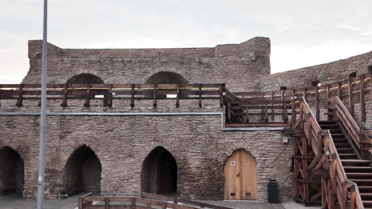 Inside the medieval Fortress of Deva, showcasing a wooden staircase leading through the fortress ruins and centuries-old stone structures