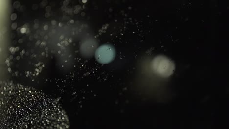 snow melts onto night windshield with defocused lights in background