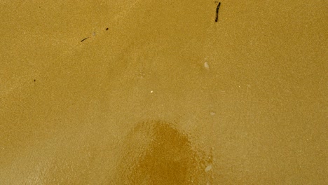 emoji. vista superior de la ola que lava el rostro triste dibujado en la arena de la playa de arena del mar mediterráneo. 4k