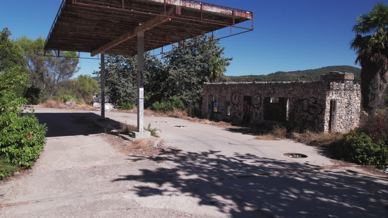 Man standing in front of abandoned gas station, camera moving forward and over it to reveal the Embalse de Entrepeñas reservoir near Madrid