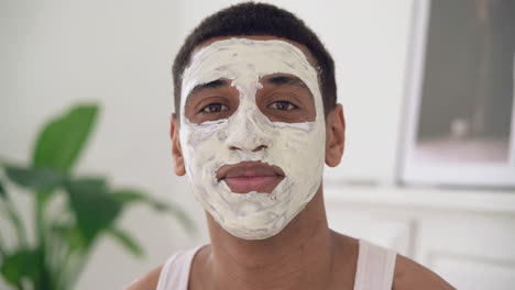 portrait of a handsome black man with facial mask looking at camera and smiling