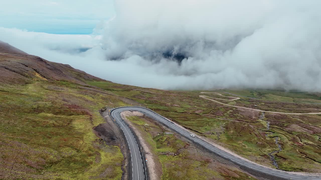 vuela sobre una carretera de asfalto en las montañas de pendiente con un paisaje de nubes en el fondo en el este de islandia