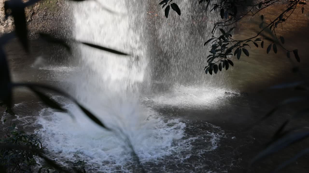 cascada salpicando en una piscina rocosa iluminada por el sol
