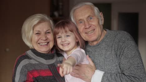 Smiling-family-grandfather,-grandmother-with-child-granddaughter-at-home