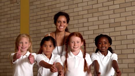 Cute-pupils-showing-thumbs-up-with-pe-teacher