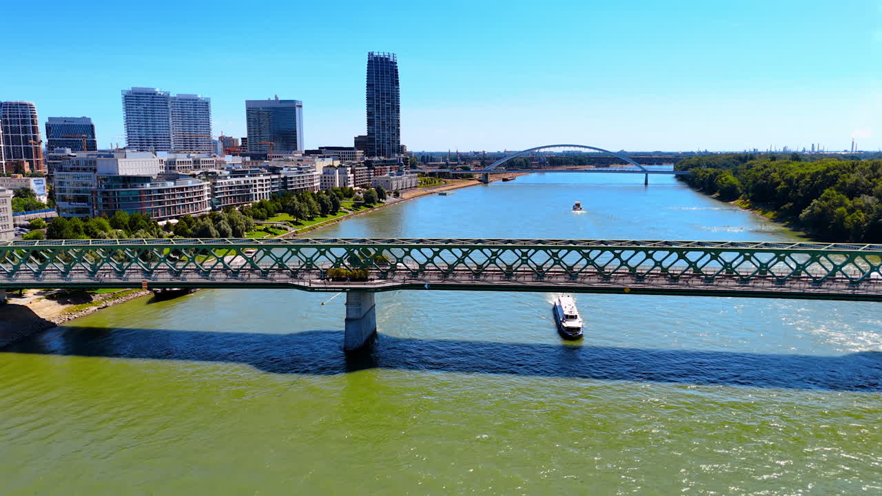 Descending over the waterscape of the Danube River flowing in Bratislava, Slovakia. View on the boats moving by the river and bridges crossing it.