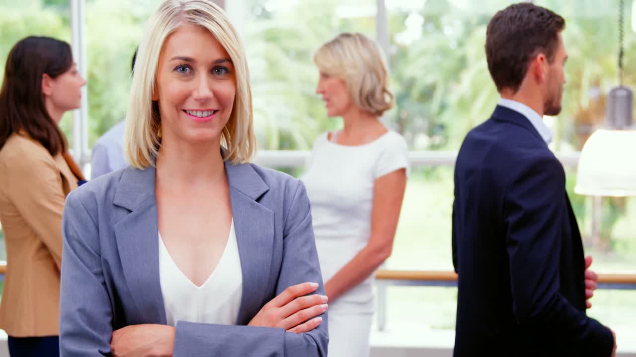 Female business executive smiling at camera while colleagues interacting in background