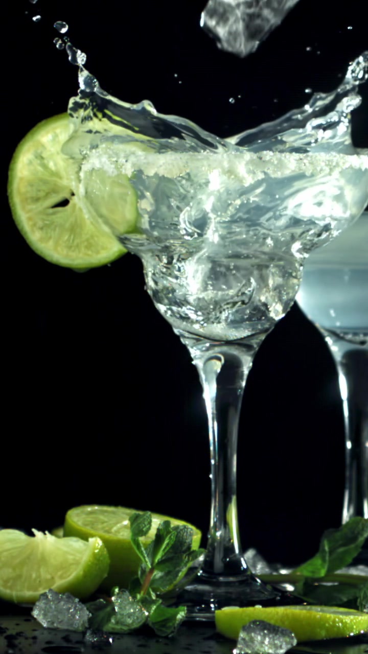 Cubetto di ghiaccio che si tuffa in un rinfrescante cocktail Margarita con lime e menta