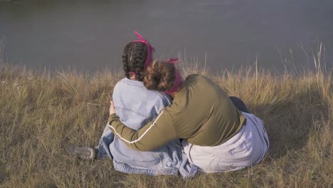 women hug having date on steep bank of river in evening