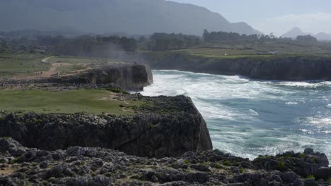 Mist-from-crashing-waves-carried-by-wind,-gulpiyuri-tunel,-bufones-de-pria-asturias-spain-sea-cliffs