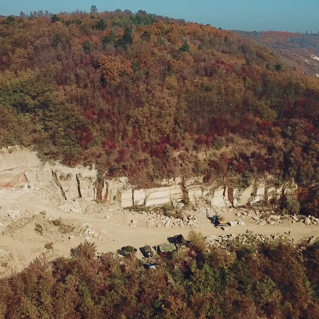 View on the work of equipment in the sand quarry on the background of the forest near the river. Camera movement down. Aerial view