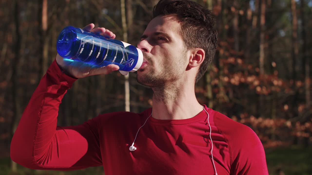 primer plano de un hombre bebiendo agua después de un entrenamiento duro