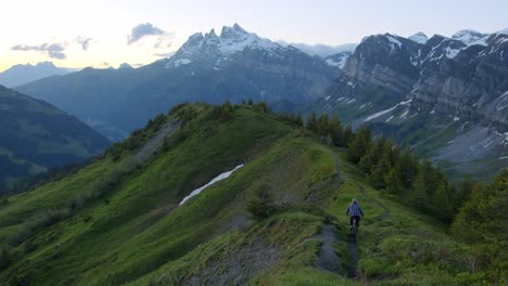 mountain biker rides down a scenic ridge at dusk