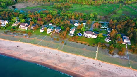 drone video captures a maine beach cottage near the ocean. real estate gem with large deck, patio, big windows, and yard steps from sandy beach. relax and enjoy atlantic waterfront paradise.