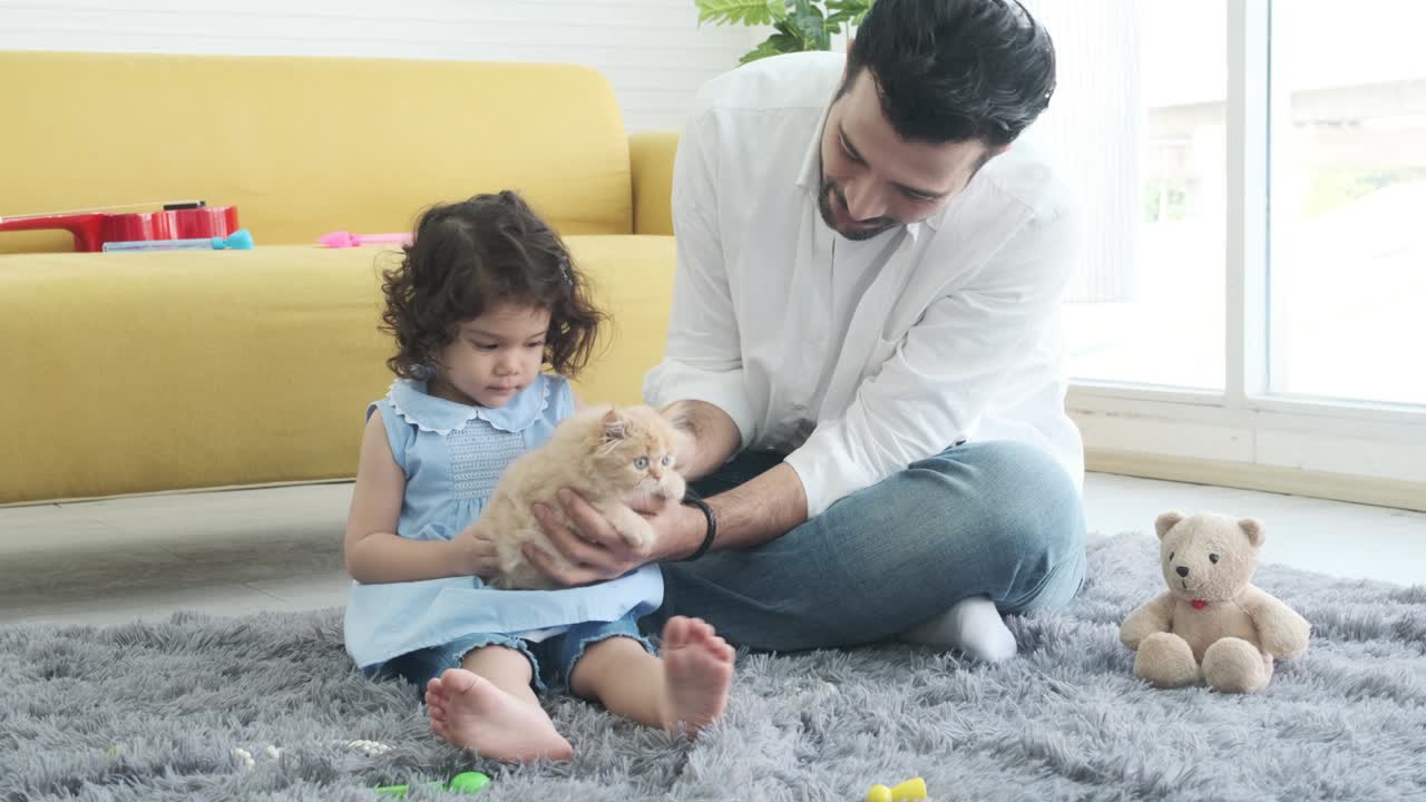 padre ayudando a su pequeña y linda hija a cuidar de un gato adorable.