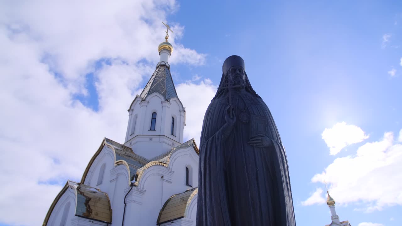 estatua de un sacerdote frente a una iglesia