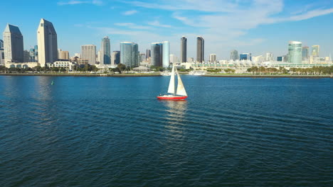 red sailboat on the san diego bay with a view of san diego's skyline