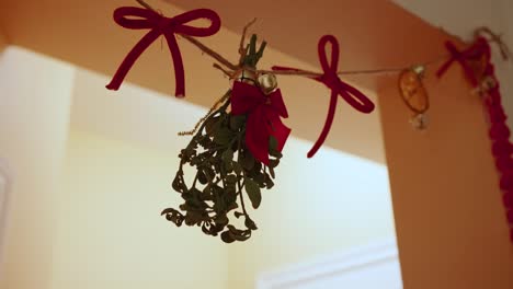 Mistletoe hangs in doorway, with red bows and twine