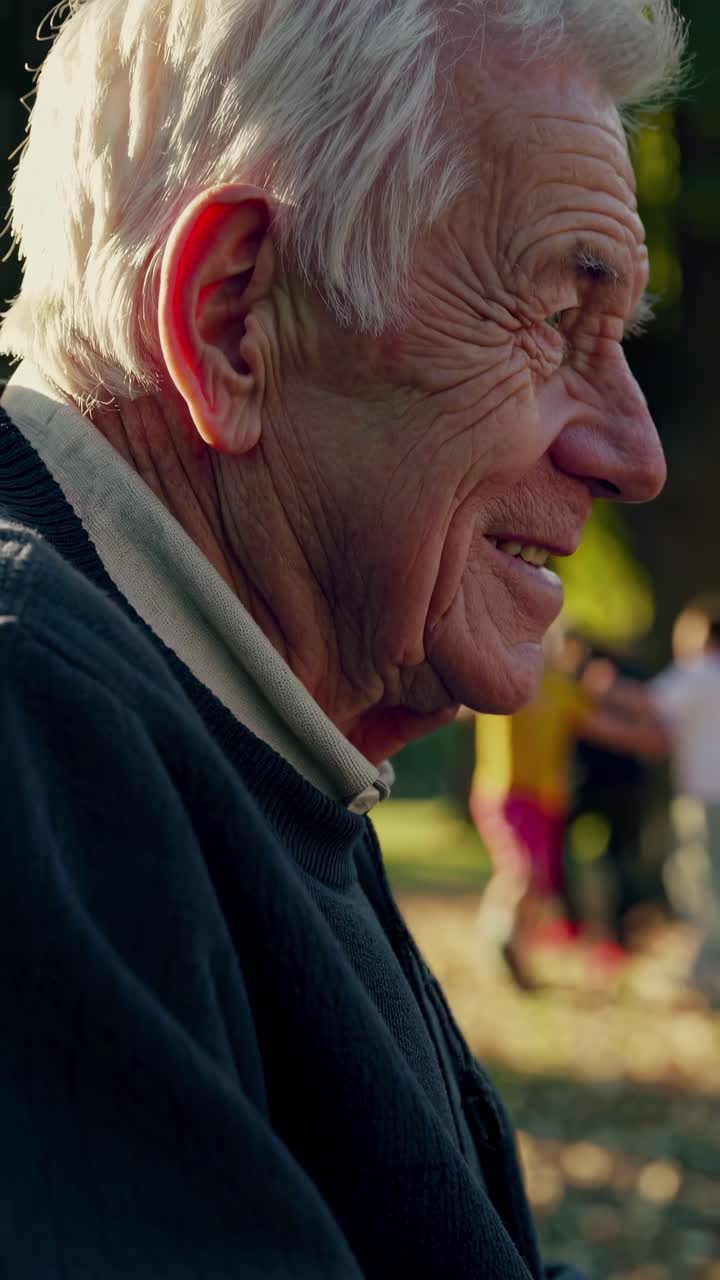 Video in stile nostalgico che mostra il profilo laterale di un uomo anziano sorridente all'aperto.