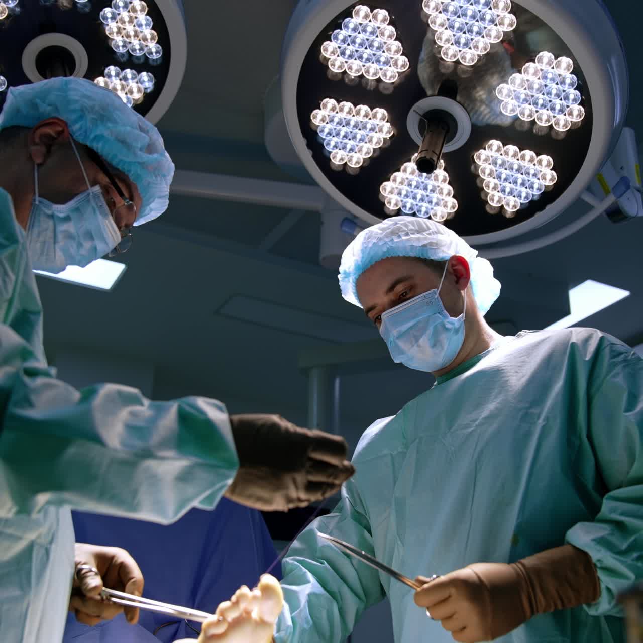 Finishing stage of an orthopedic operation. Surgeon sewing the operated foot with thread and forceps. Low angle view