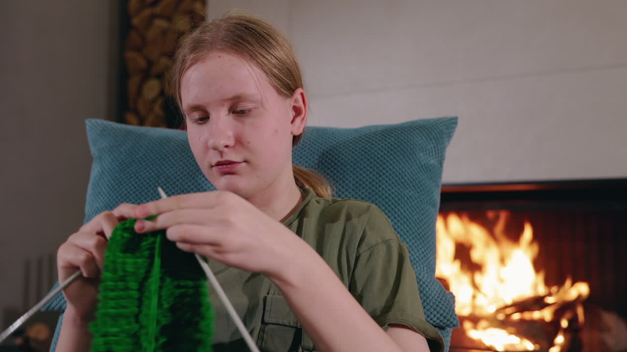 женщина вяжет у камина.