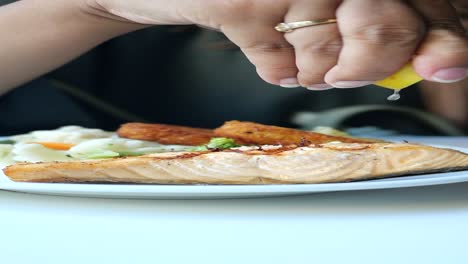 mujer comiendo salmón a la parrilla con limón