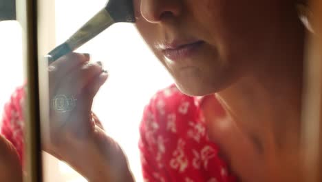 Bright-airy-cinematic-clip-of-beautiful-young-women-lady-girl-putting-powder-face-makeup-on-with-brush,-wearing-a-red-shirt-and-large-wedding-ring