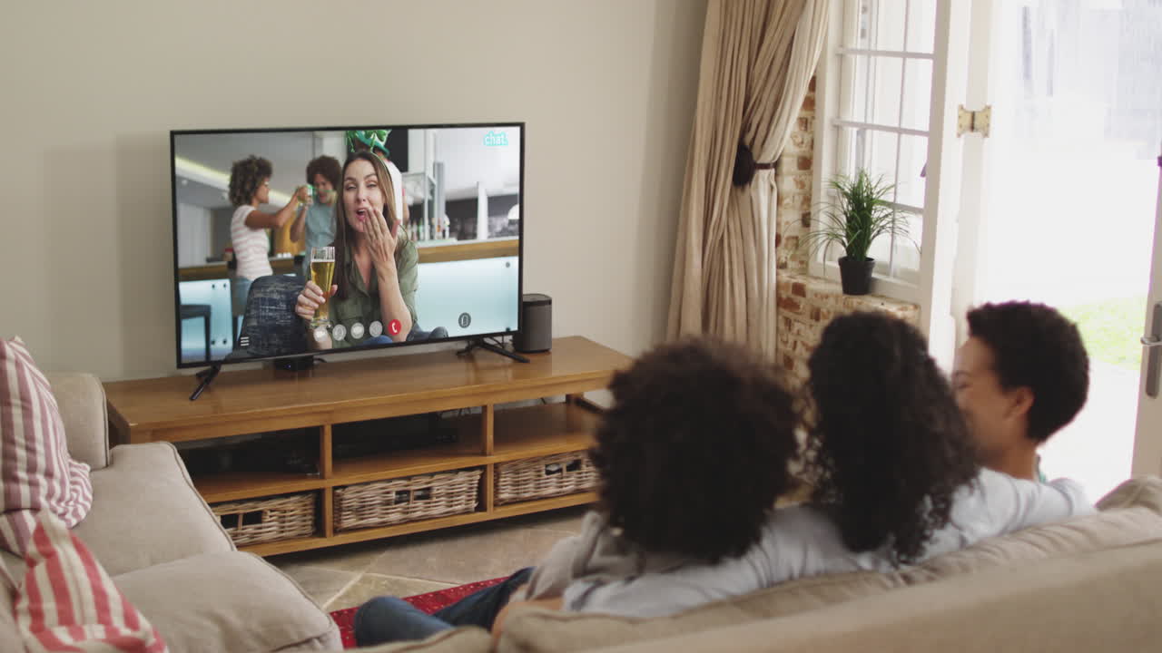 Famiglia afroamericana a casa che usa la smart TV per fare una videochiamata nel giorno di San Patrizio.