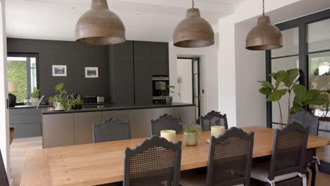 a modern kitchen with a wooden dining table and black chairs