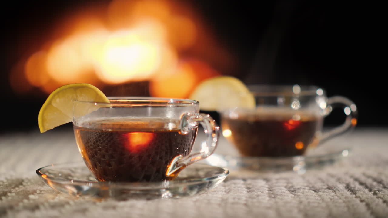 벽난로 뒤에 레몬을 넣은 차 두 잔은 흰색 니트 식탁보 위에 서 있다