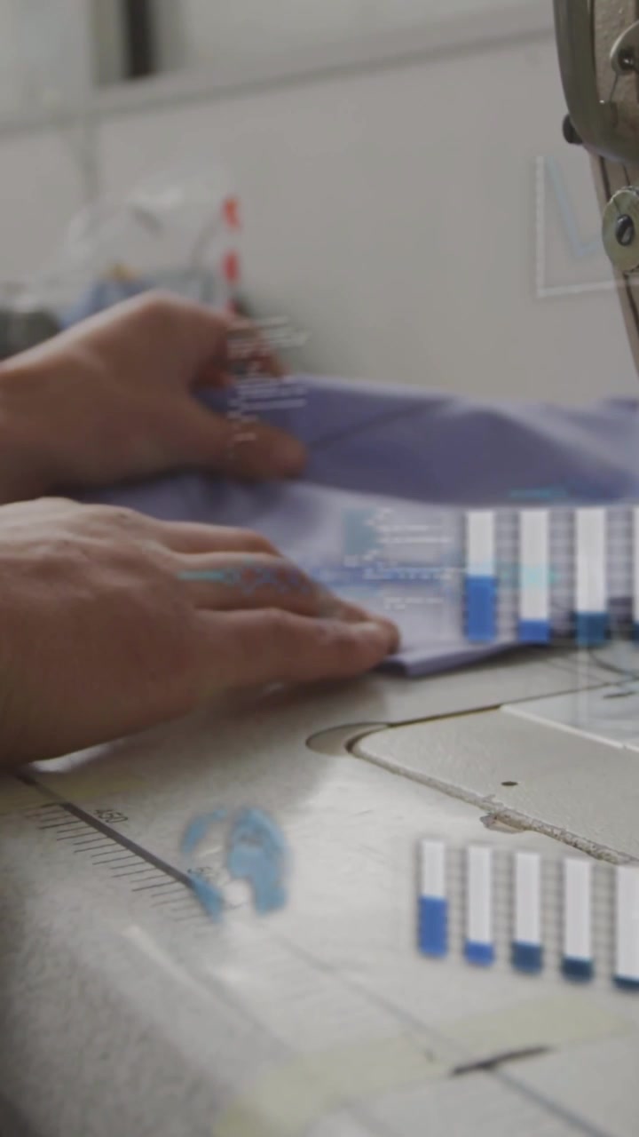 Vertical video: Tailor placing folded blue cloth on machine, guiding straight seam with HUD bars