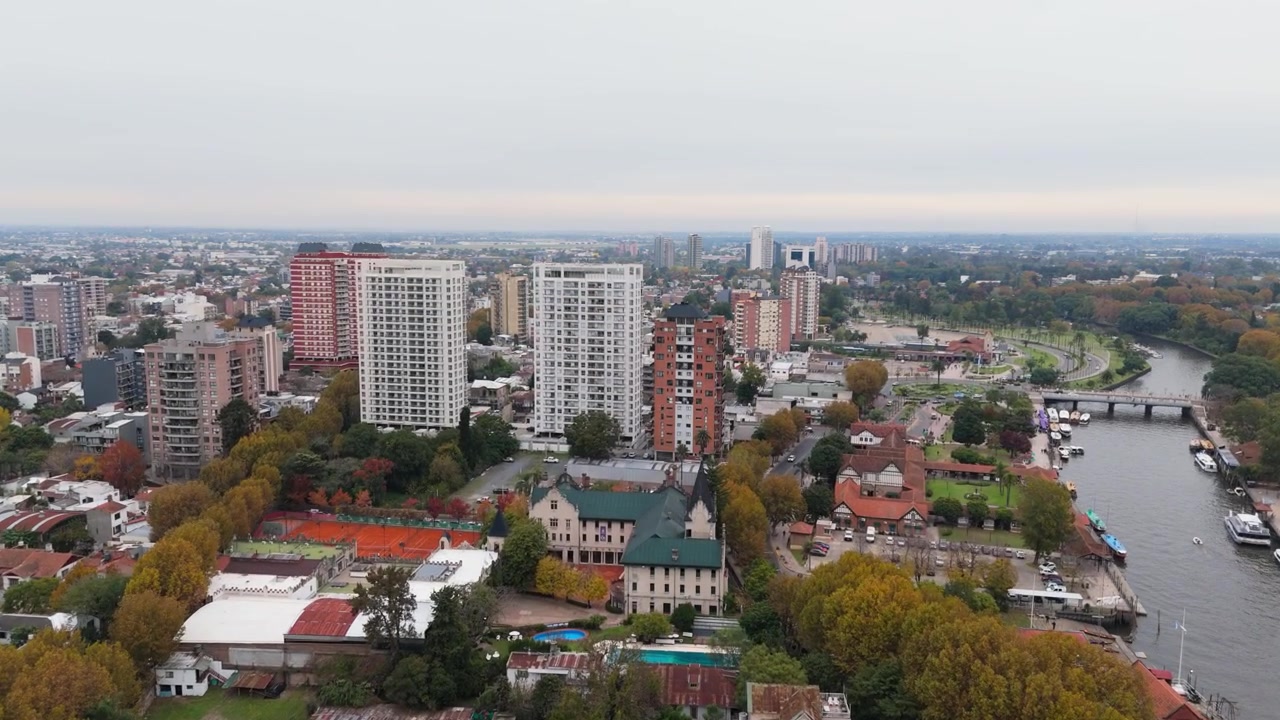 Luftfoto af byens flodbred med højhuse og både på en overskyet dag.