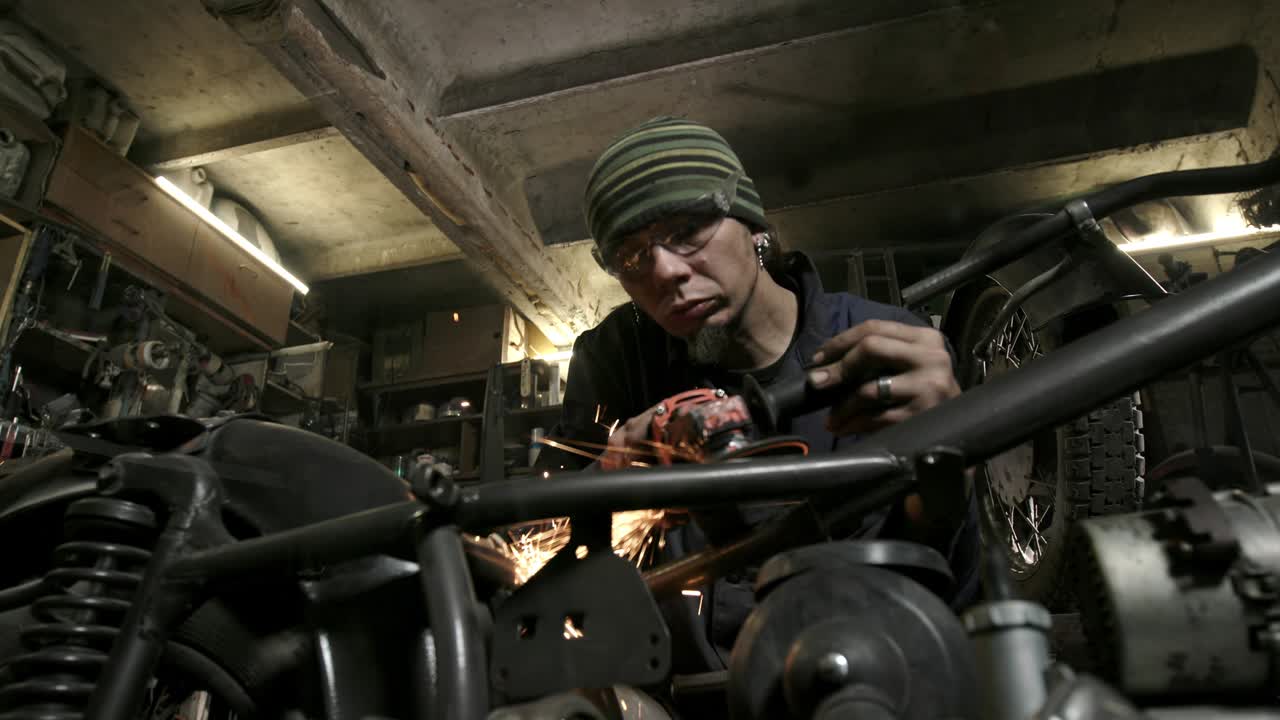 joven confiado moliendo con chispas en el taller de reparación