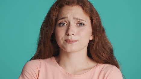 Redheaded-girl-in-front-of-camera-on-turquoise-background.